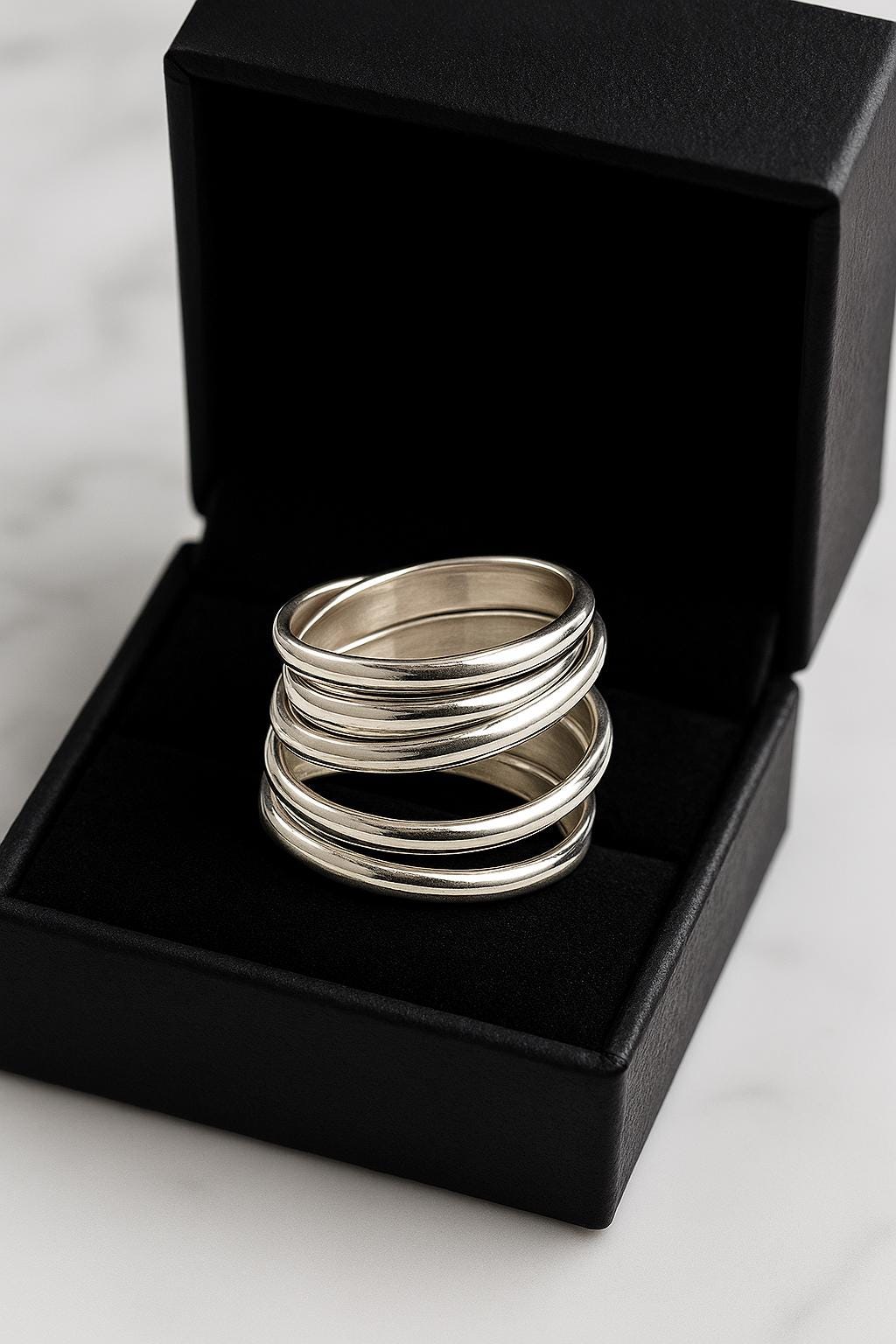 Stack of silver rings in an open black box on a marble surface