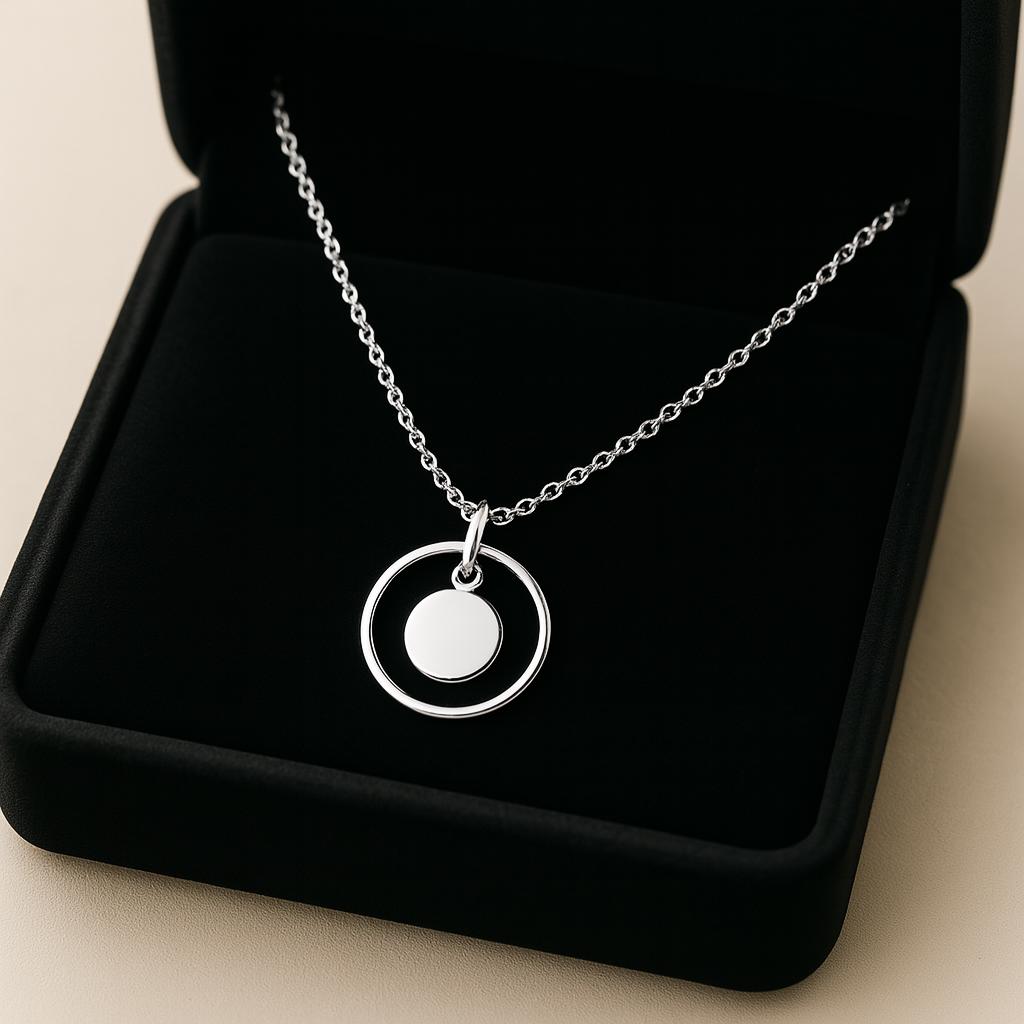 Silver necklace with a pendant in an open black jewelry box on a beige background