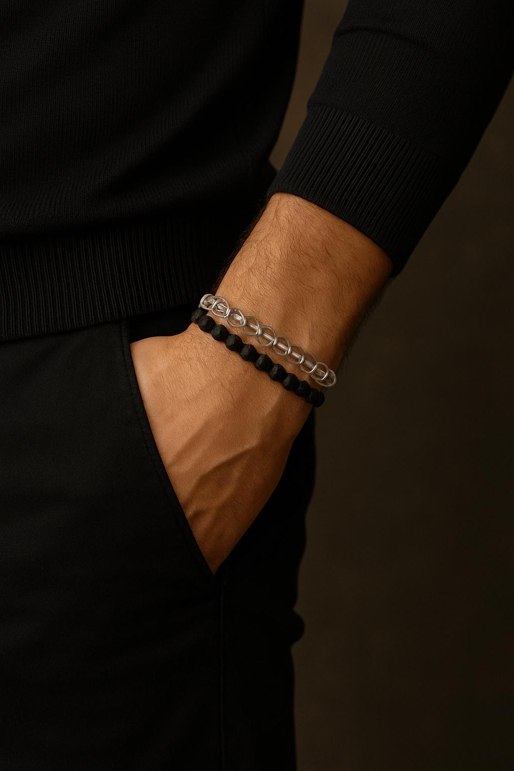 Person wearing a black beaded bracelet on a dark background