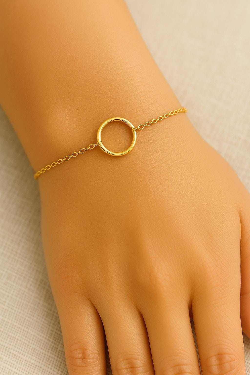 Gold bracelet with a circular design on a wrist against a neutral background
