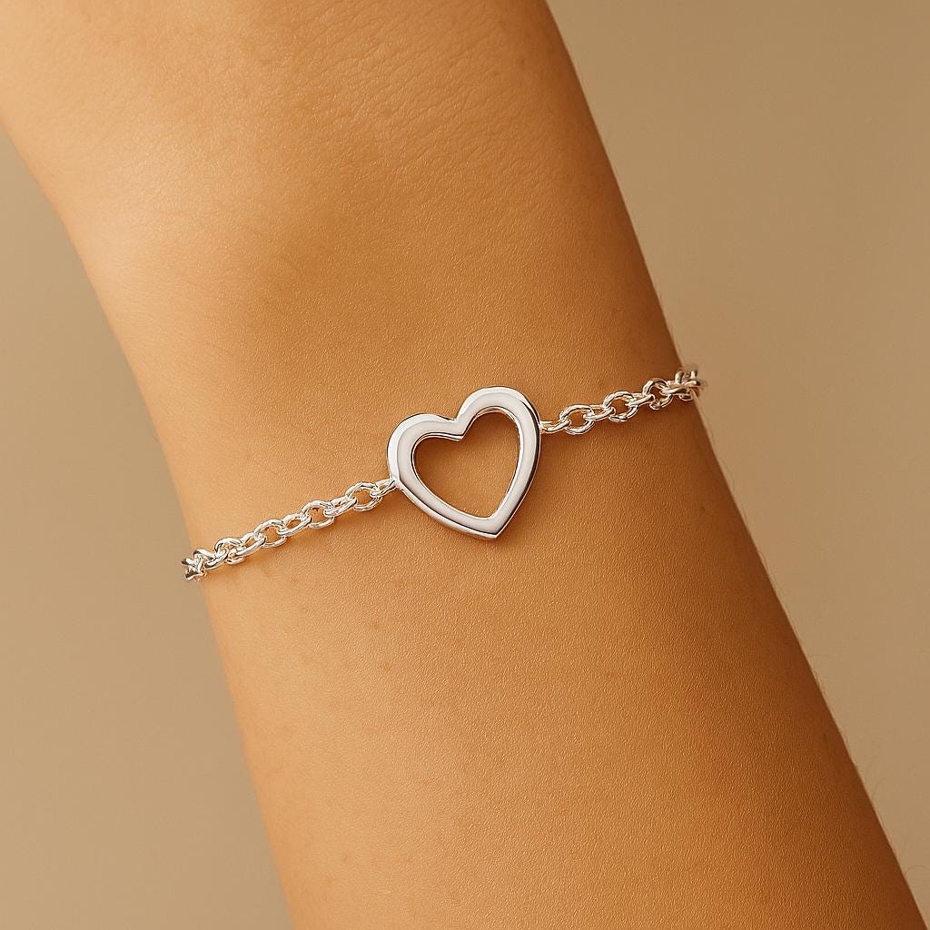 Silver heart-shaped bracelet on a wrist against a beige background