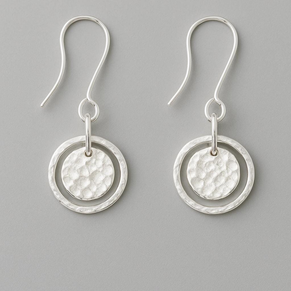 Pair of silver earrings with circular designs on a gray background