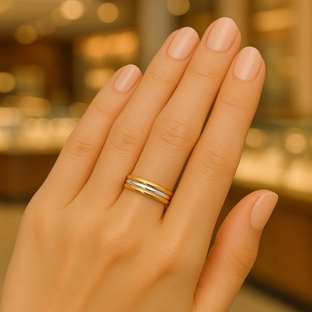 Hand wearing a gold ring with a blurred warm-toned background
