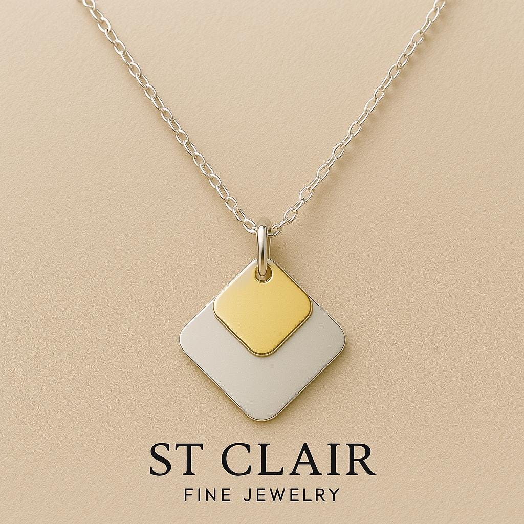 Necklace with gold and silver pendant on a beige background, featuring 'St. Clair Fine Jewelry'.