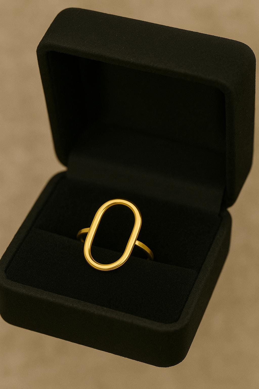 Gold ring in a black jewelry box on a beige background