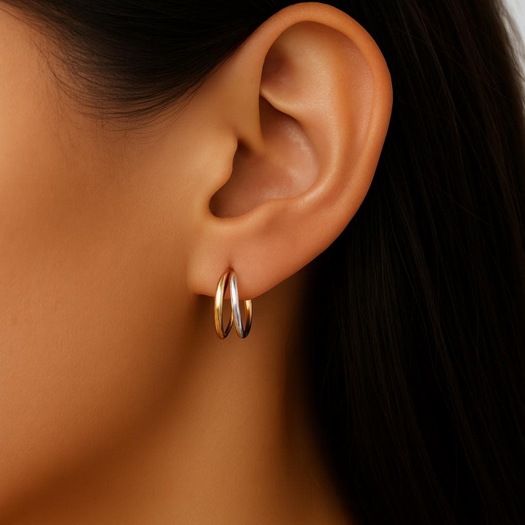 Close-up of an ear wearing two gold hoop earrings with a blurred background