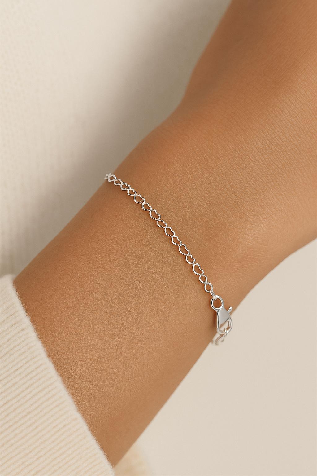 Silver chain bracelet on a wrist with a neutral background
