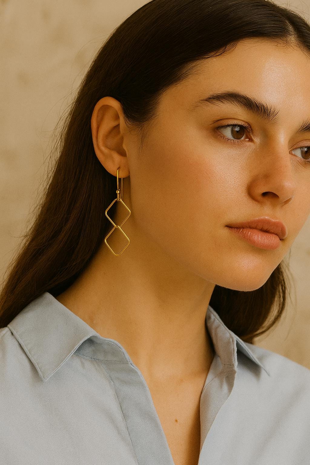 Woman wearing gold earrings with a neutral background