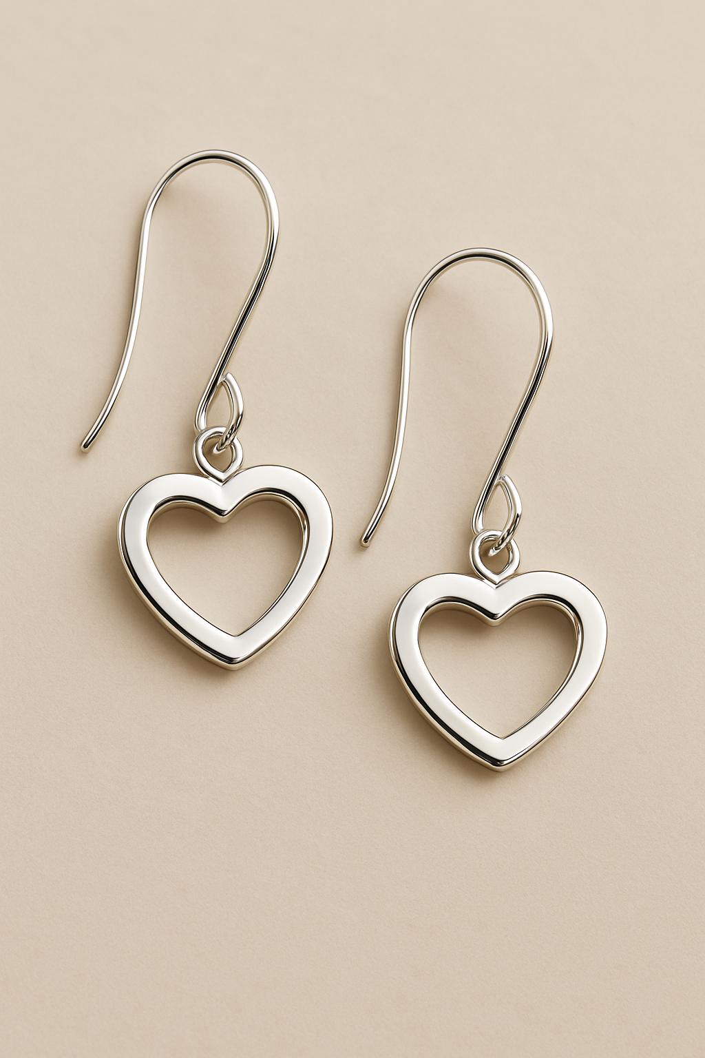Silver heart-shaped earrings on a beige background