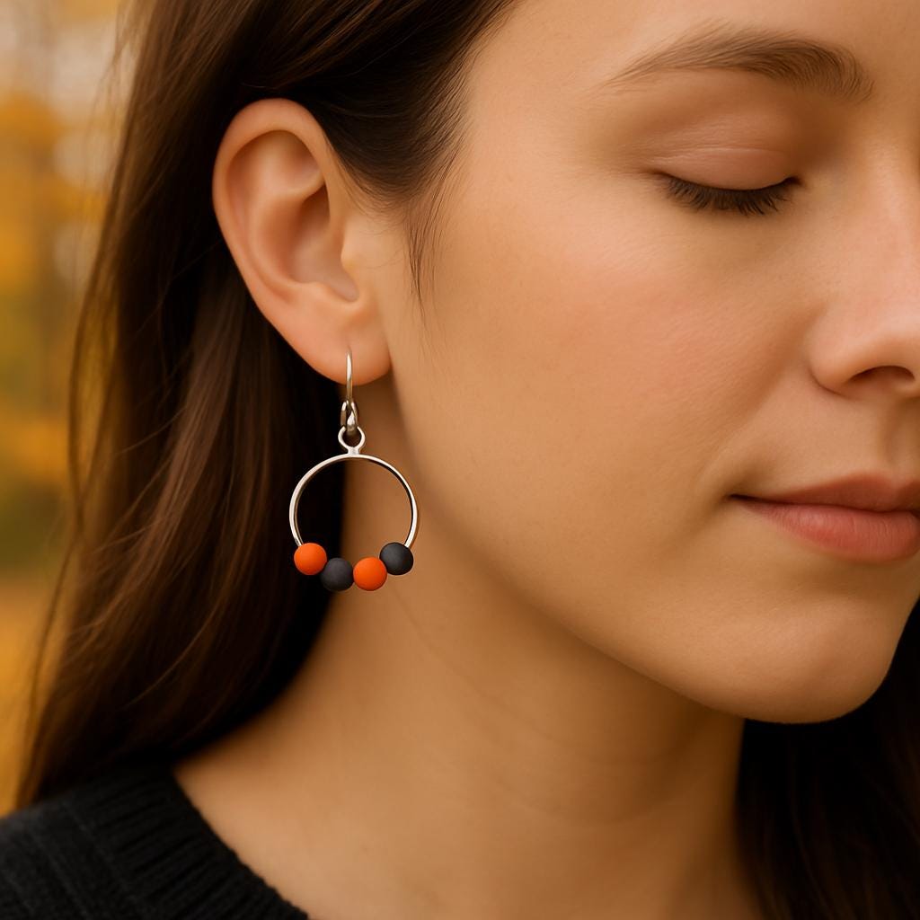 Close-up of a woman wearing a hoop earring with colorful beads against a blurred natural background.