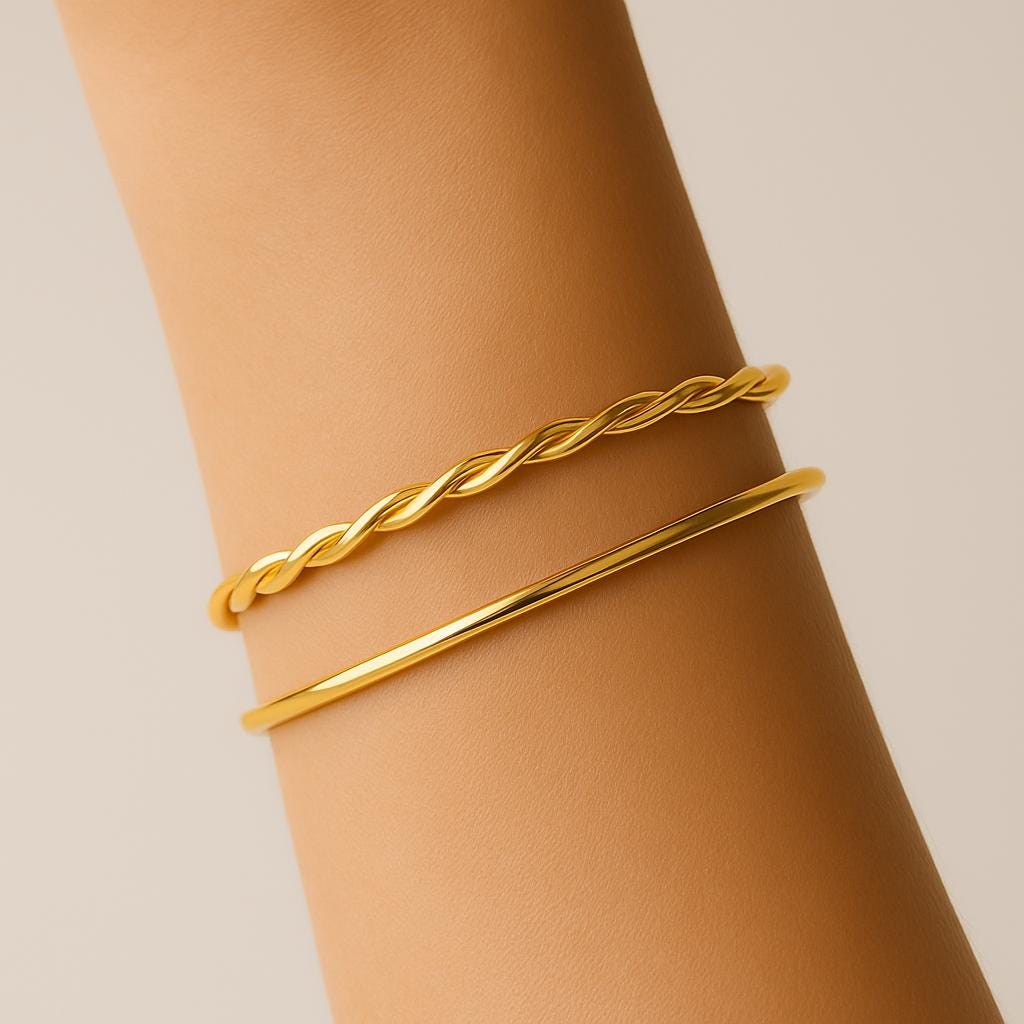 Gold braided bracelet on a wrist against a beige background