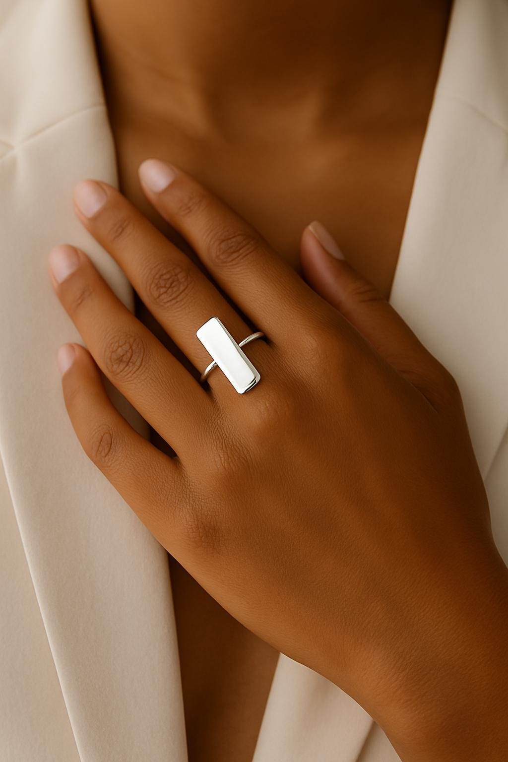 Hand wearing a silver ring with a neutral background