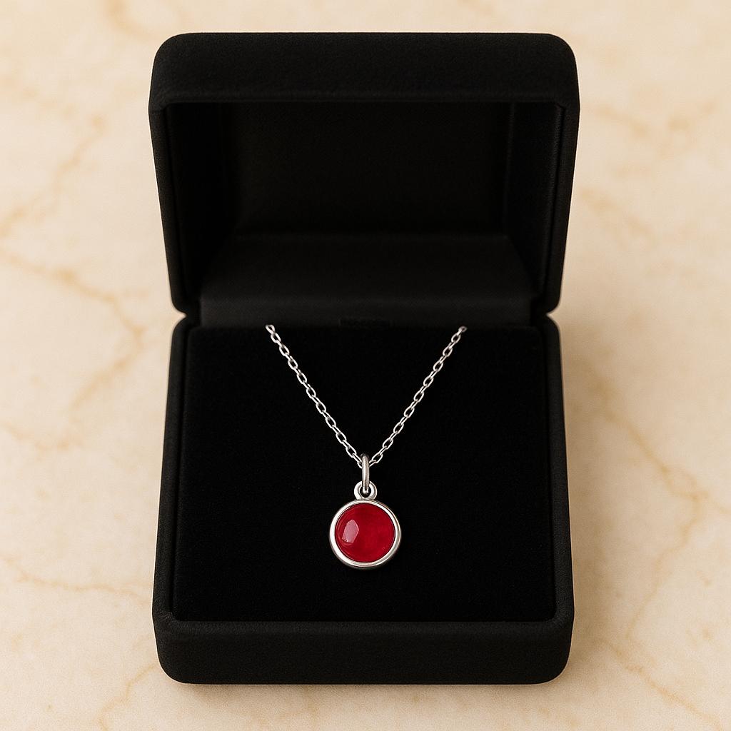 Necklace with a red pendant in a black jewelry box on a beige surface