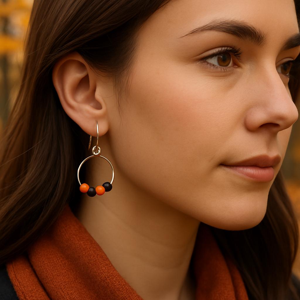 Close-up of a woman wearing a hoop earring with colorful beads, set against a blurred autumn background.