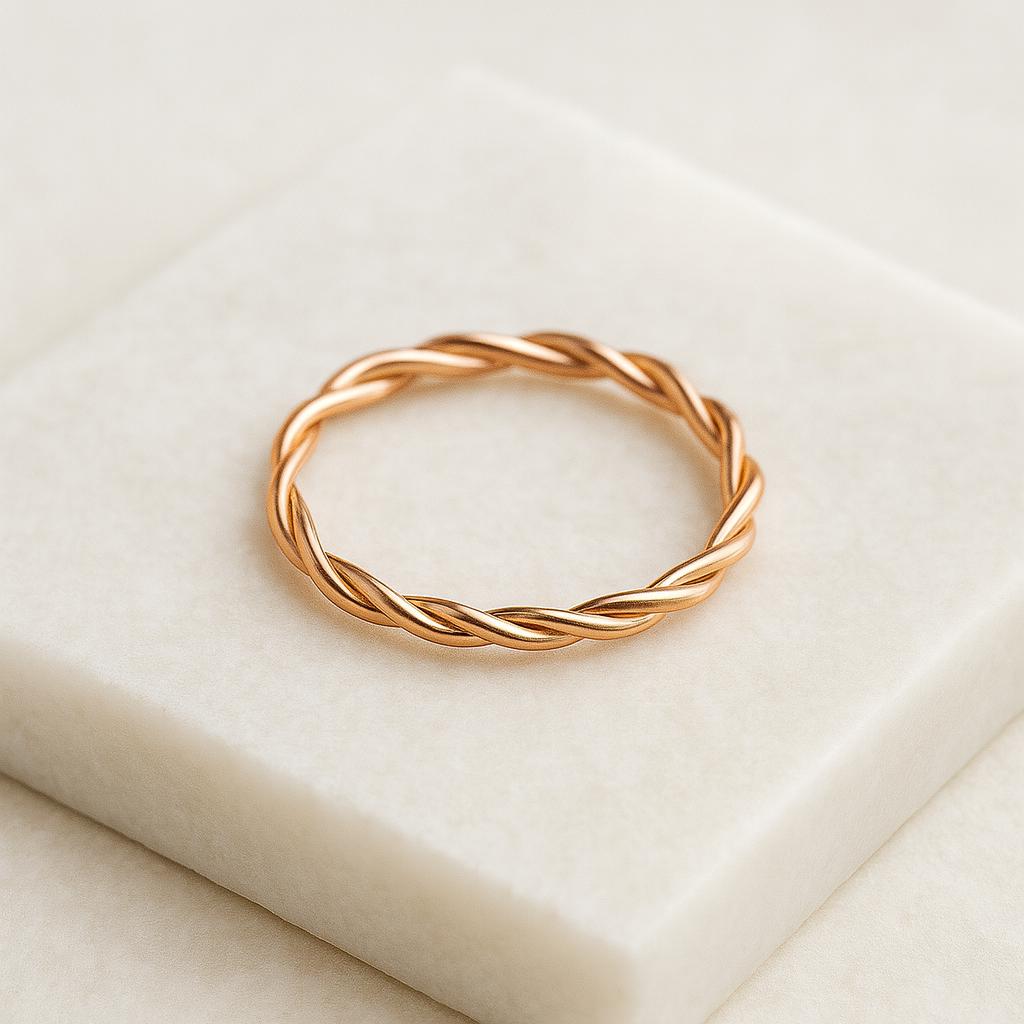Rose gold twisted ring on a beige fabric background