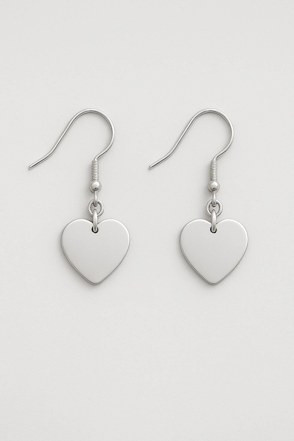 Silver heart-shaped earrings on a light gray background