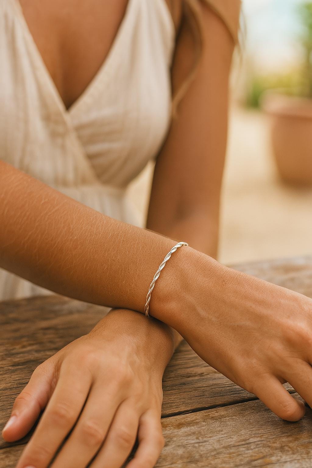 Close-up of a person's wrist wearing a silver bracelet on a wooden surface.