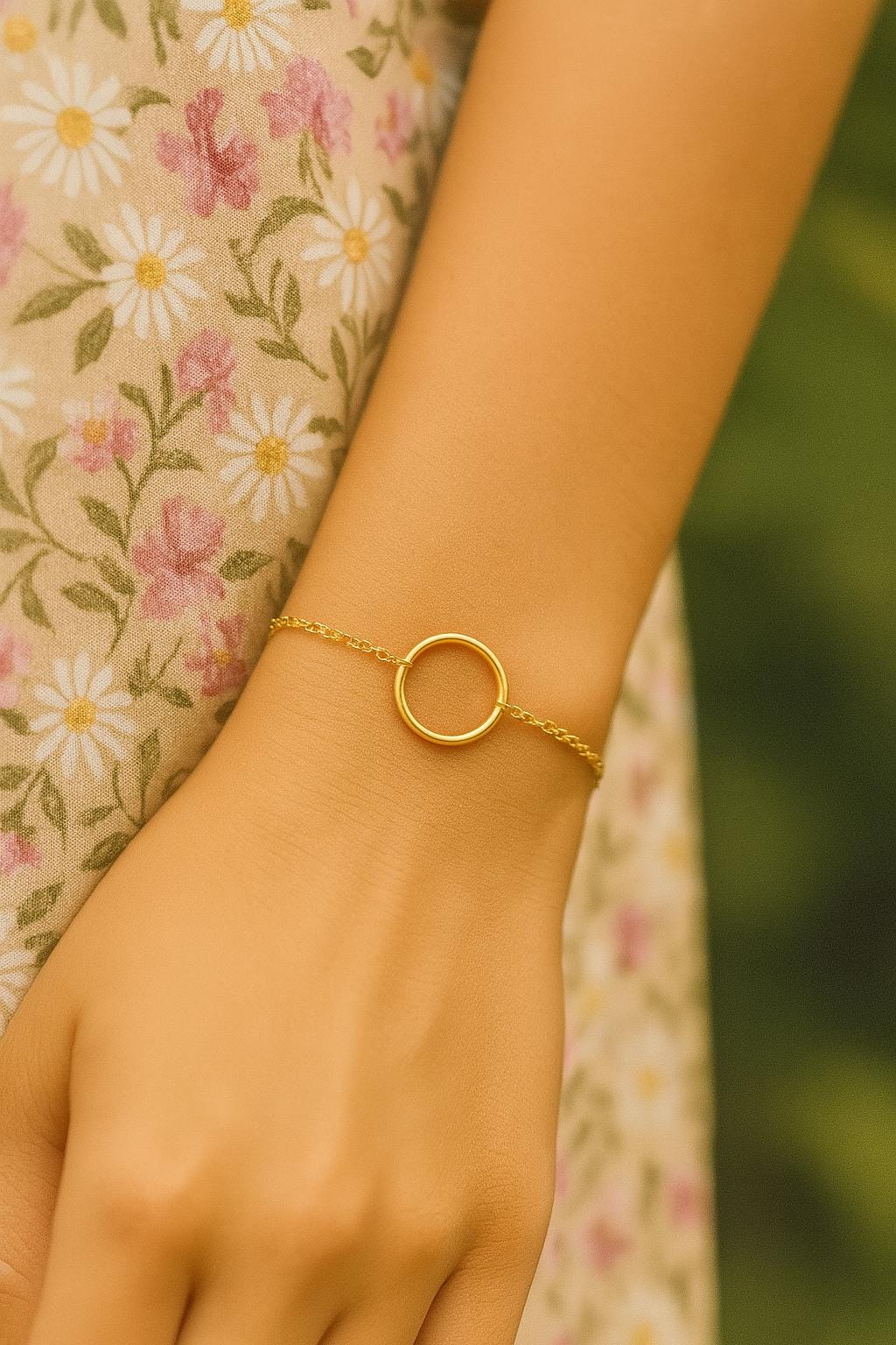 Gold bracelet on a wrist with a floral-patterned fabric background