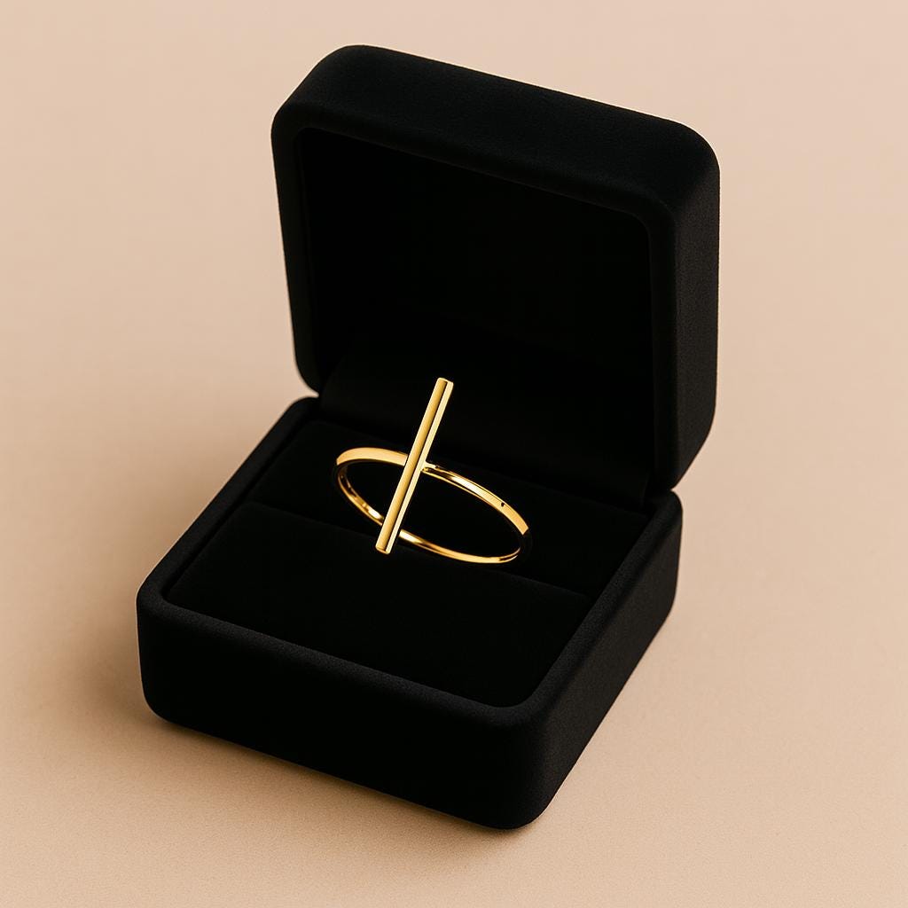 Gold ring in an open black velvet jewelry box on a beige background