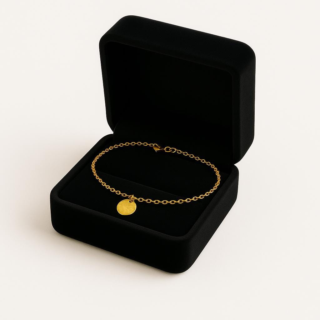 Gold bracelet with a round pendant in an open black jewelry box on a white background