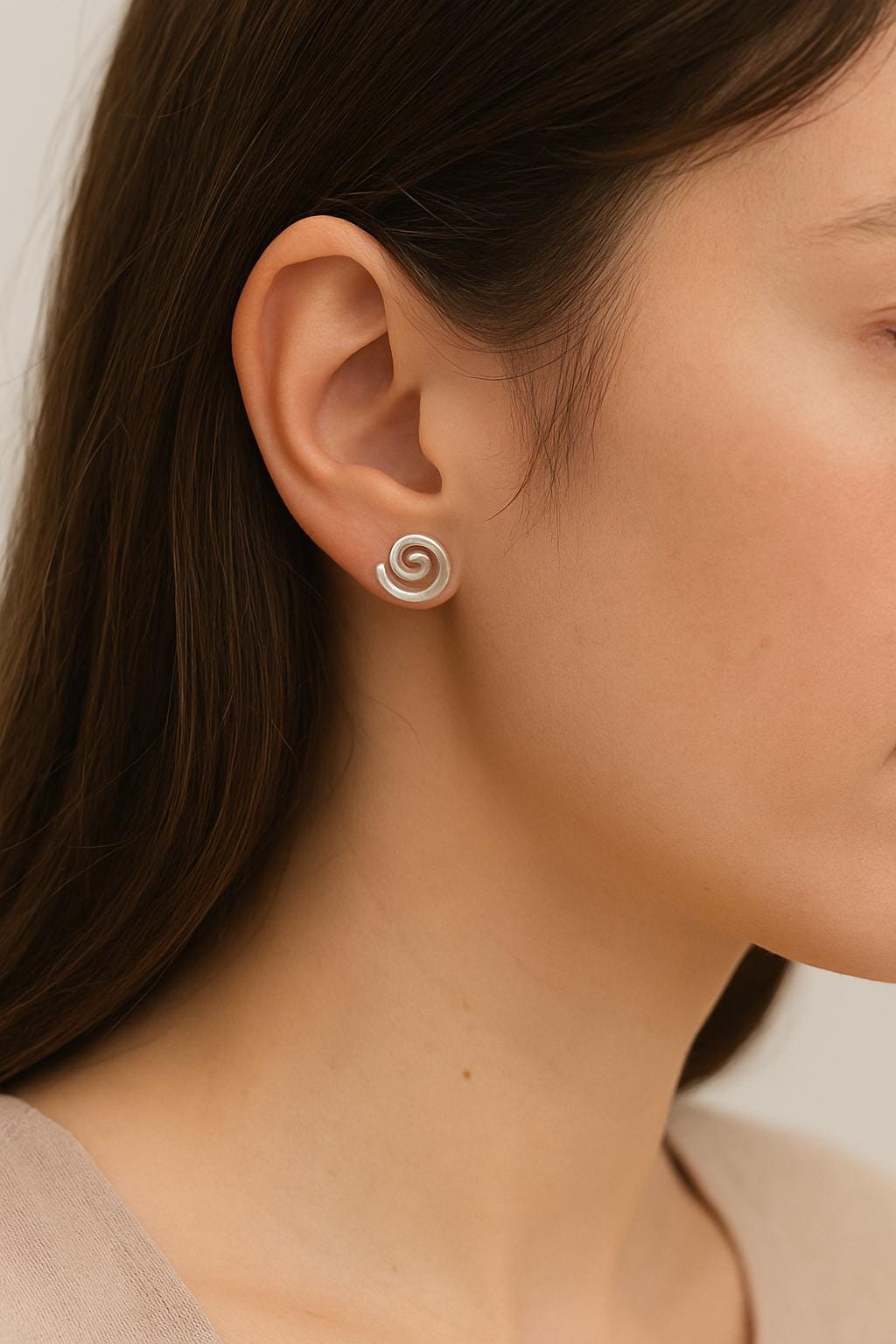 Close-up of a person wearing a spiral earring with a neutral background