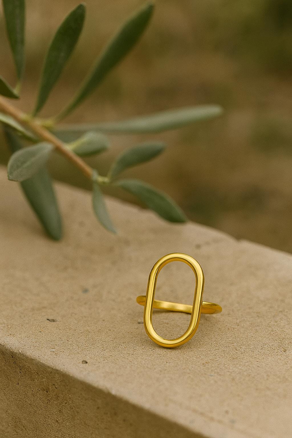 Gold ring on a textured surface with green leaves in the background