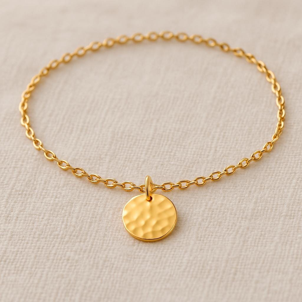 Gold bracelet with a round pendant on a beige background