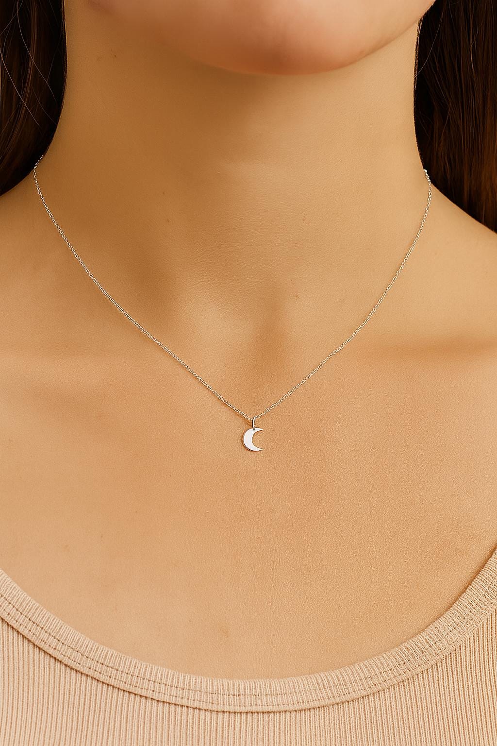 Silver necklace with a moon pendant on a model wearing a beige top.