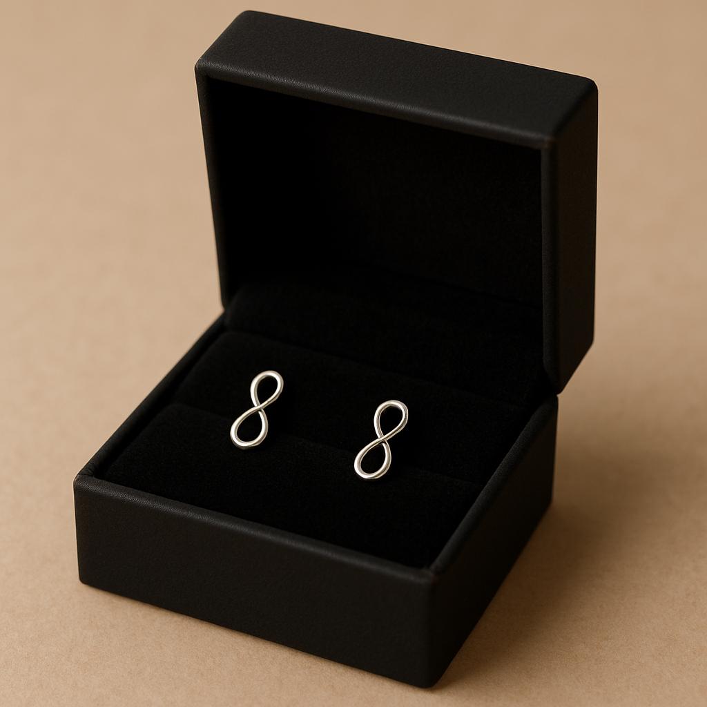 Silver infinity symbol earrings in a black jewelry box on a beige background