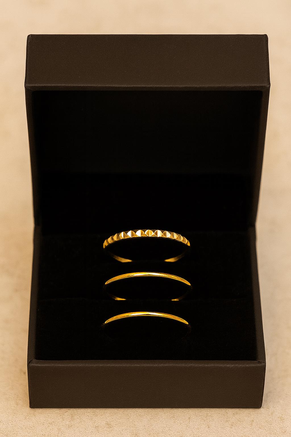Gold bracelets in an open black jewelry box on a beige background
