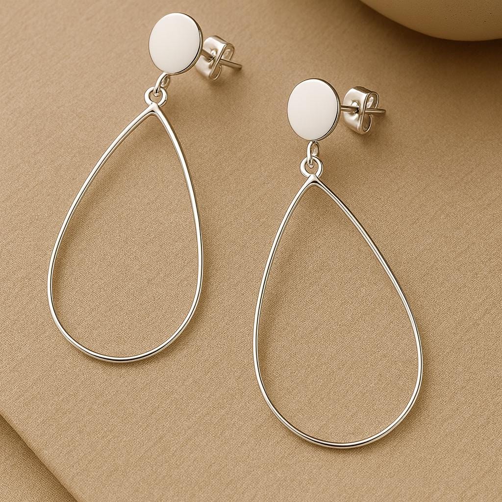 Silver teardrop earrings on a beige background