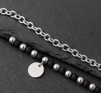 Silver chain bracelet with black beads on a dark surface