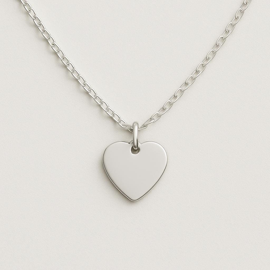 Silver heart-shaped pendant on a chain against a light gray background