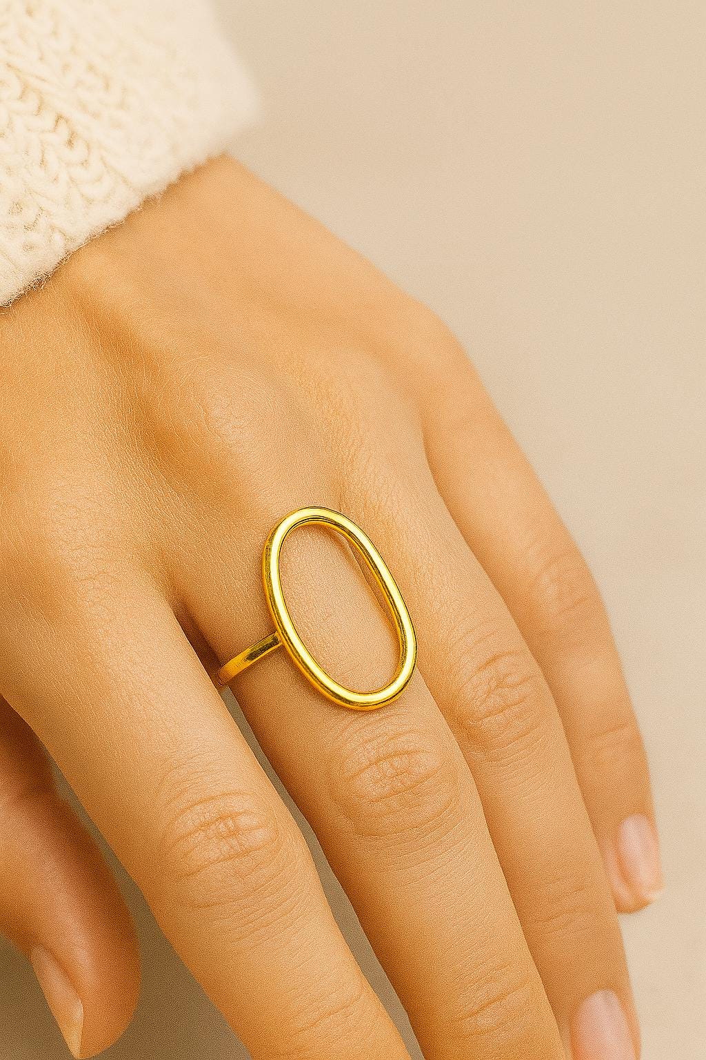 Gold ring on a person's finger against a beige background