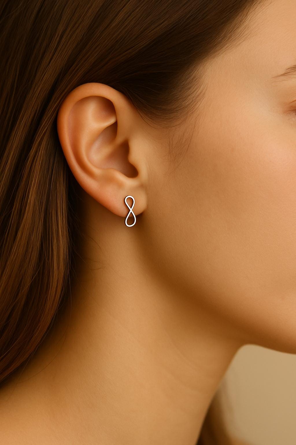 Close-up of a person wearing a silver infinity symbol earring.