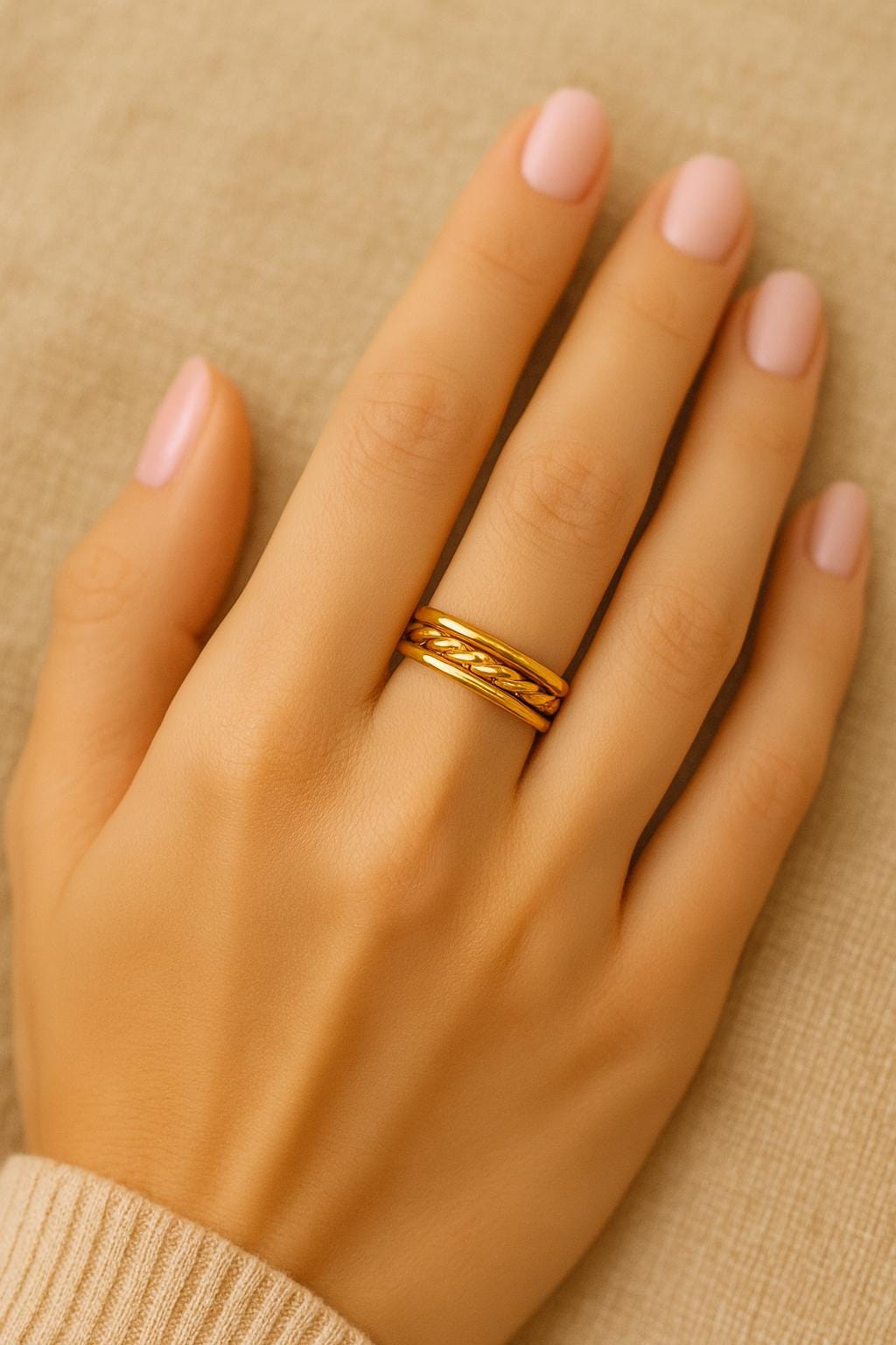 Gold ring on a hand with a beige background