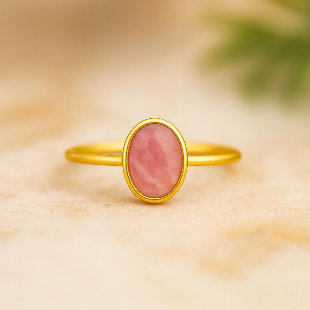 Gold ring with a pink gemstone on a beige background