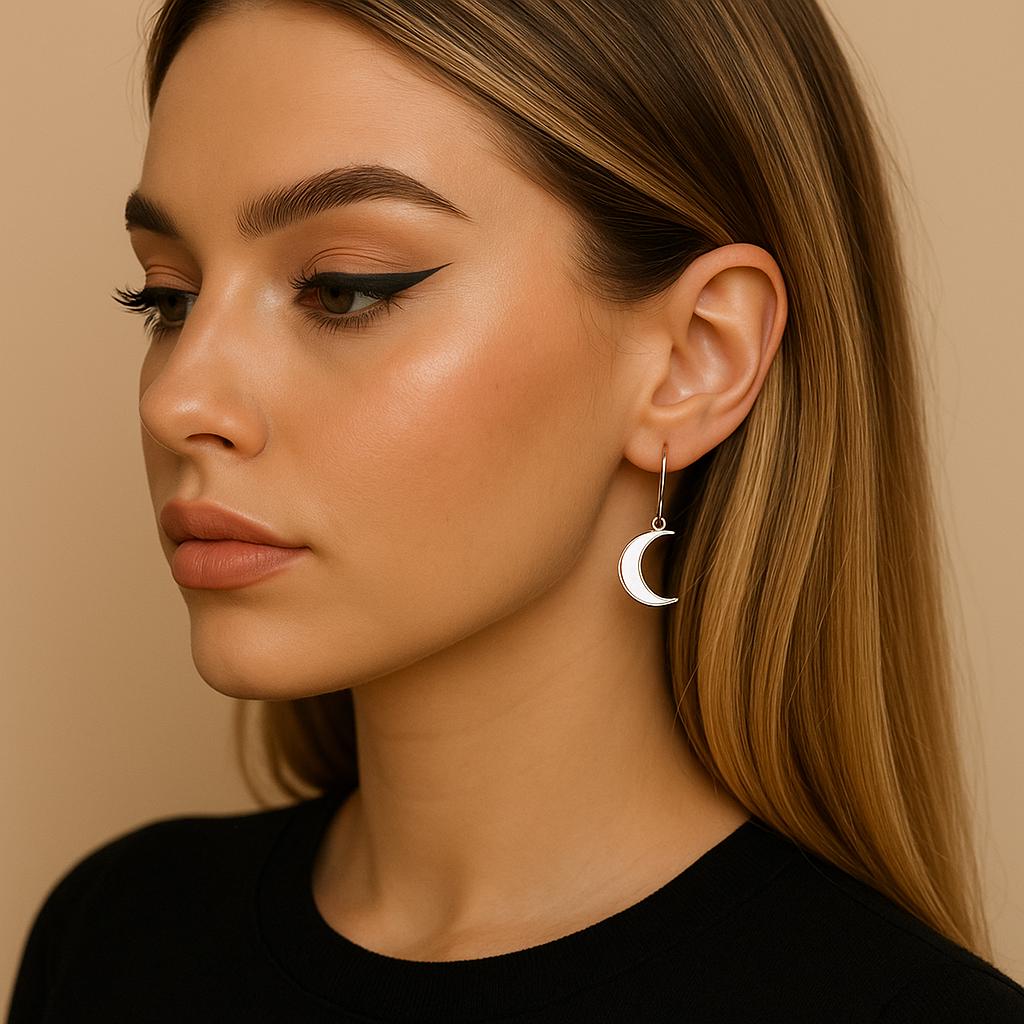 Close-up of a woman wearing a silver moon-shaped earring against a beige background
