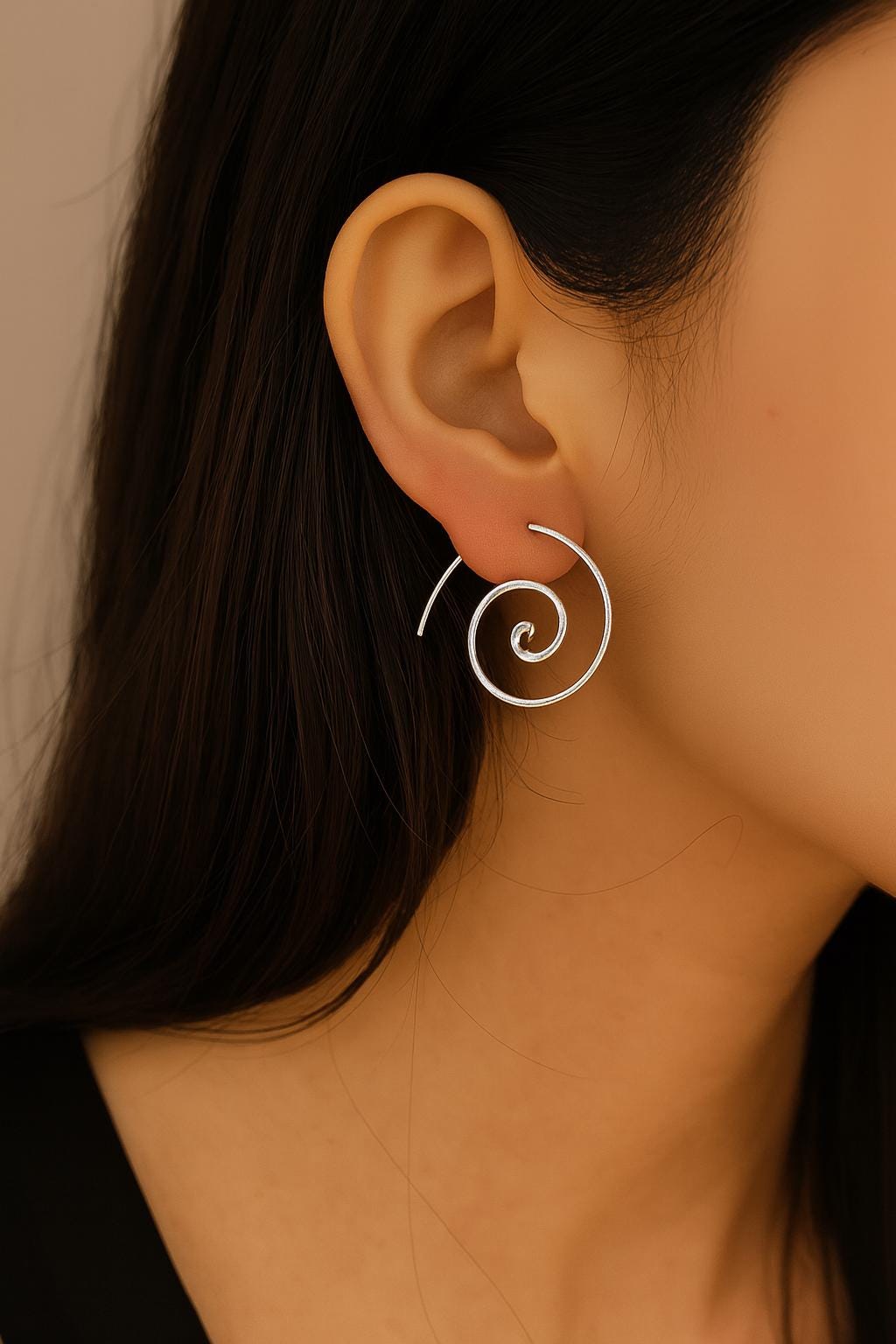 Close-up of an ear wearing a silver spiral earring with a neutral background