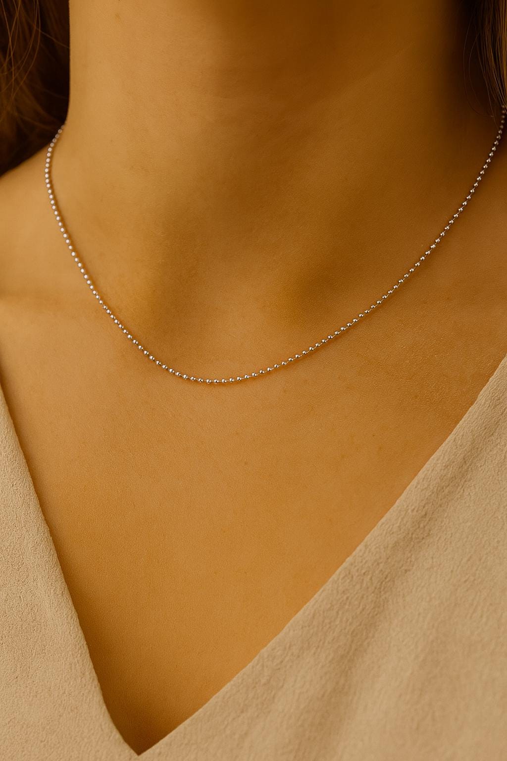 Silver necklace on a person wearing a beige top