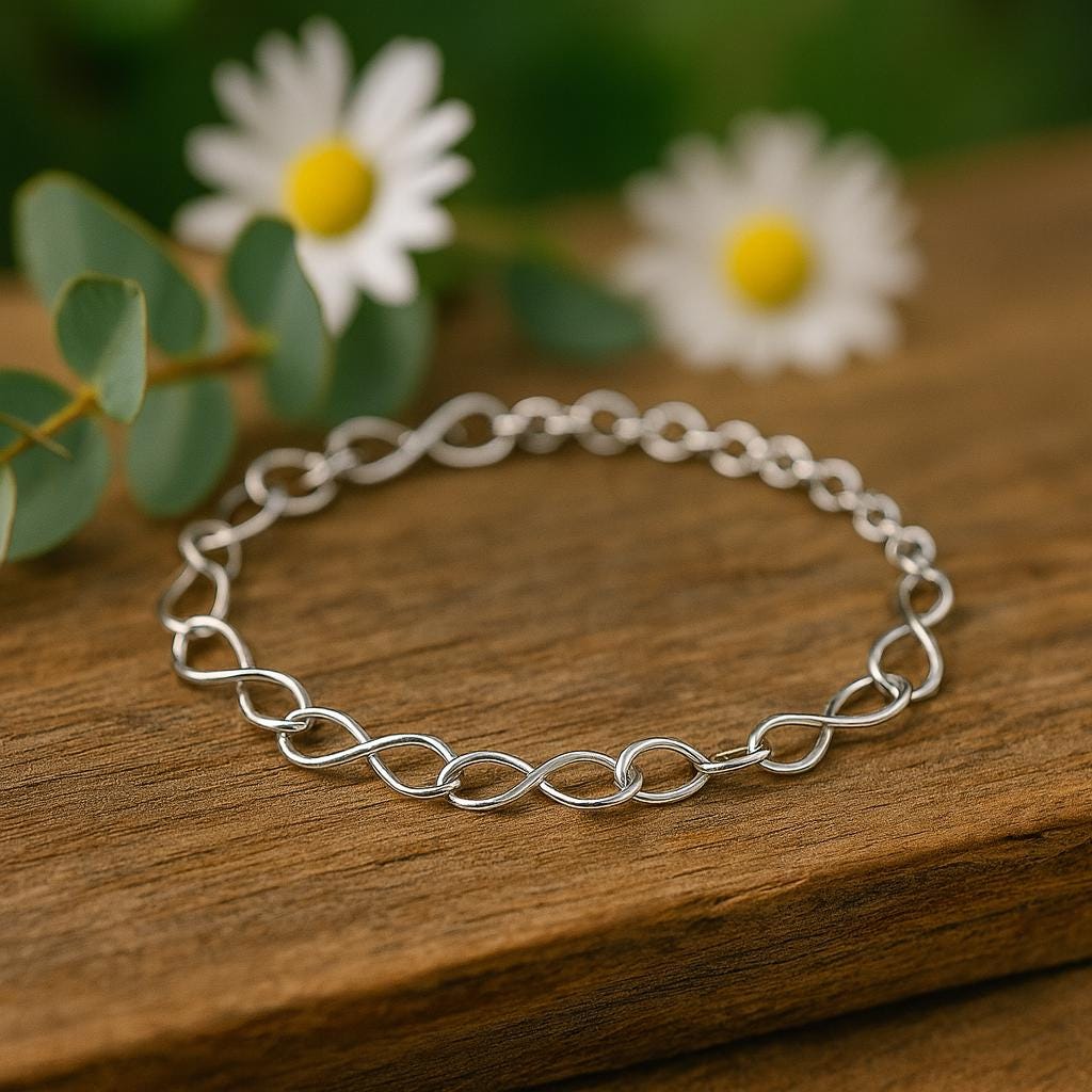 Silver chain bracelet on a wooden surface with daisies in the background