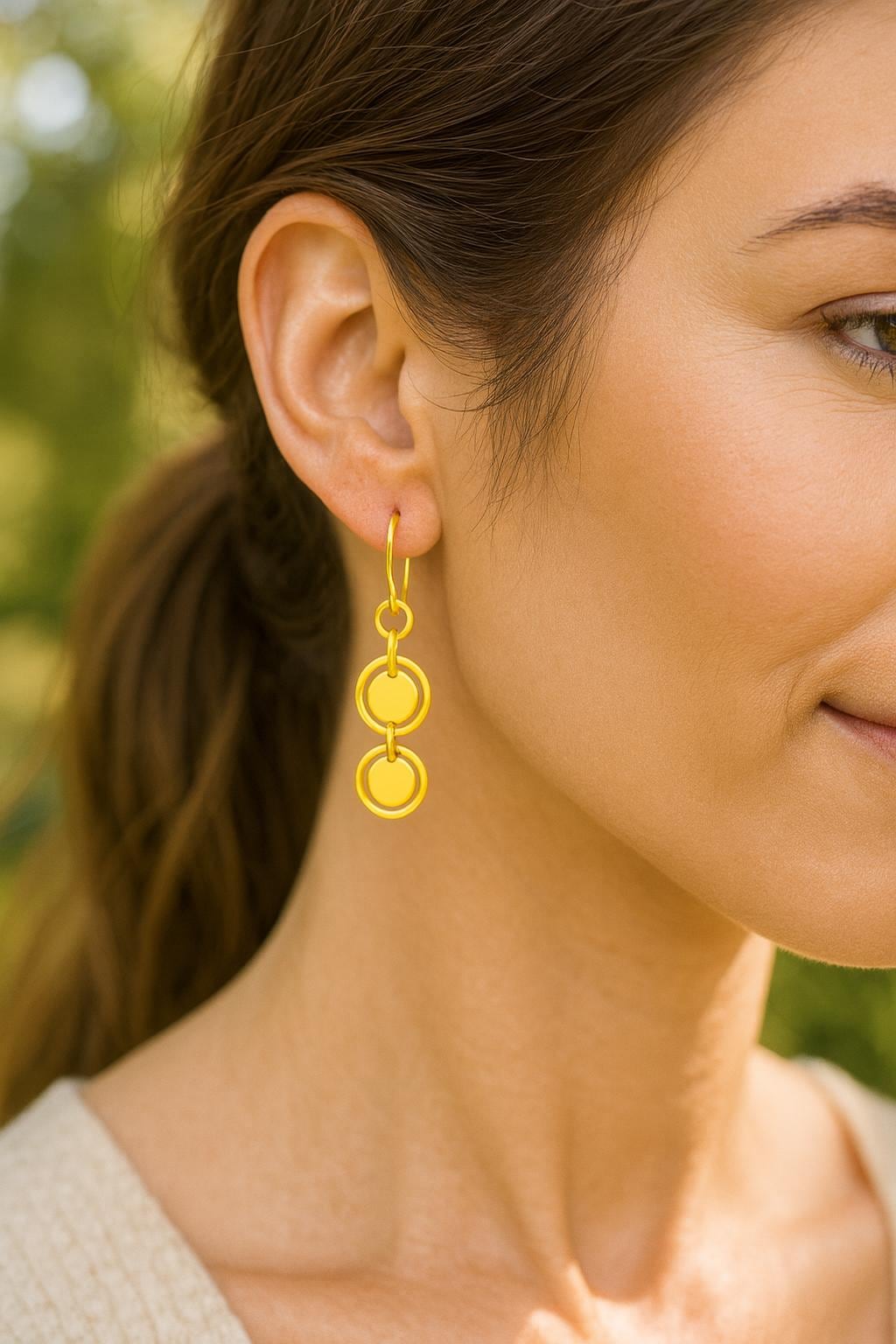 Close-up of a woman wearing gold earrings with a blurred natural background