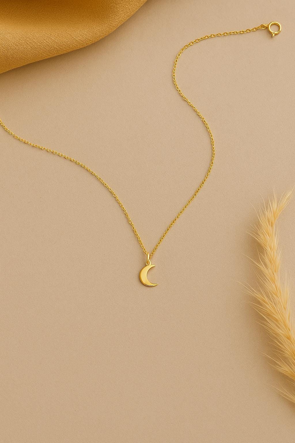 Gold necklace with a crescent moon pendant on a beige background