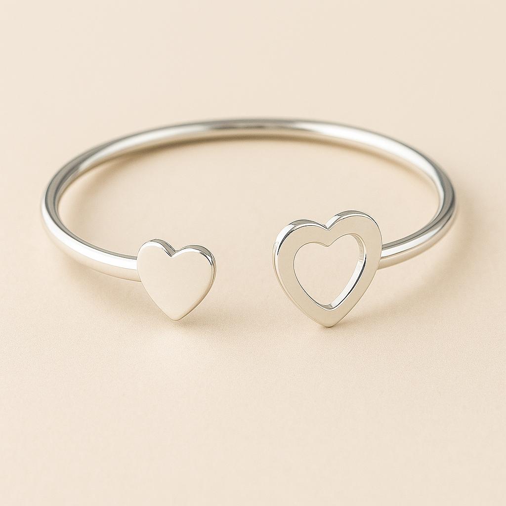 Silver bangle with heart-shaped ends on a beige background