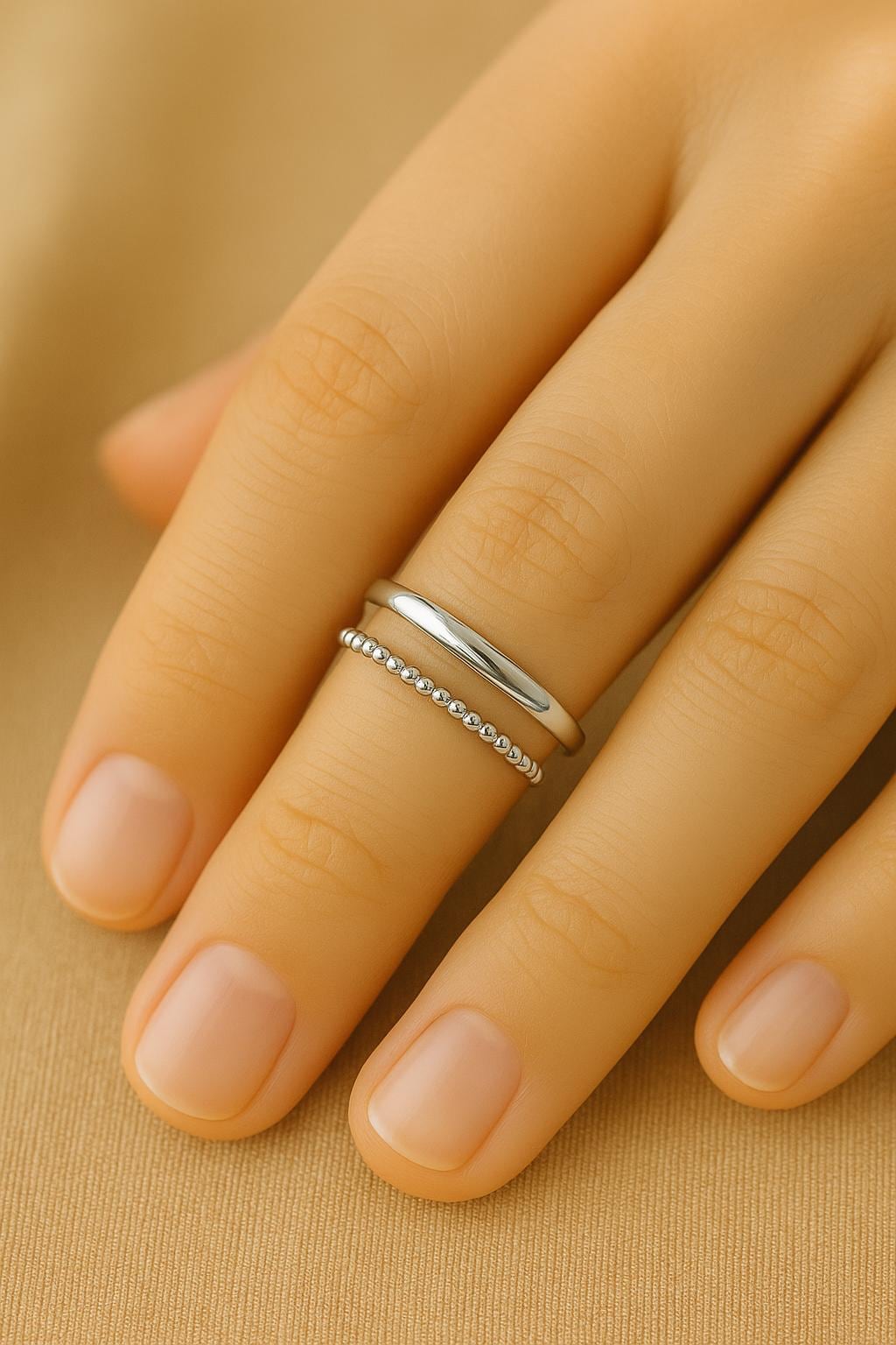 Silver ring on a person's finger against a beige background