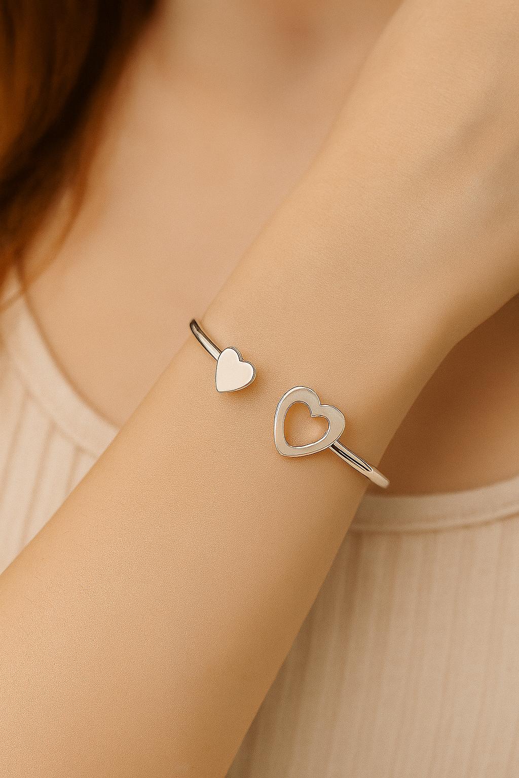 Silver heart-shaped bracelet on a person's wrist with a soft background