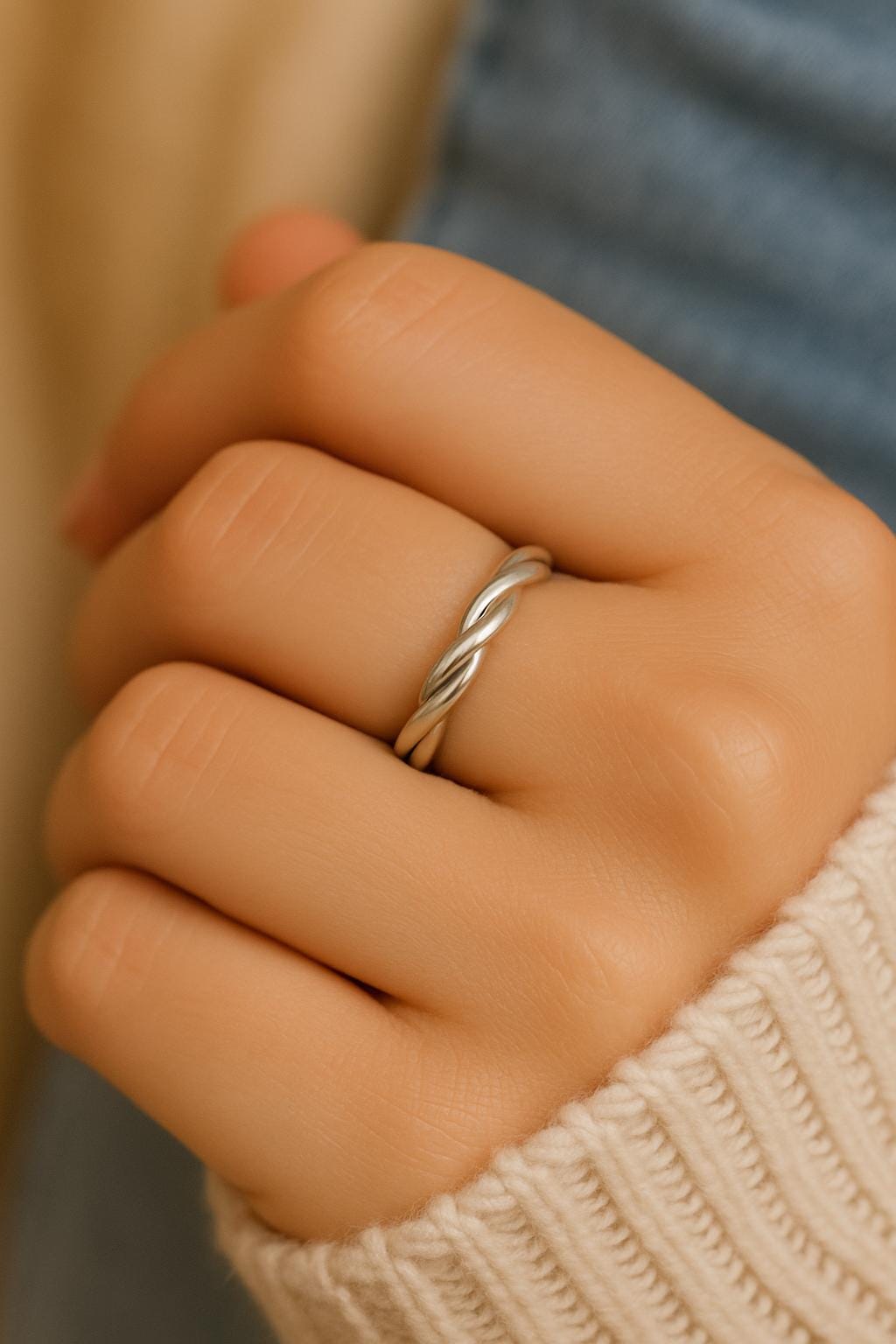 Close-up of a hand wearing a silver ring with a blurred background