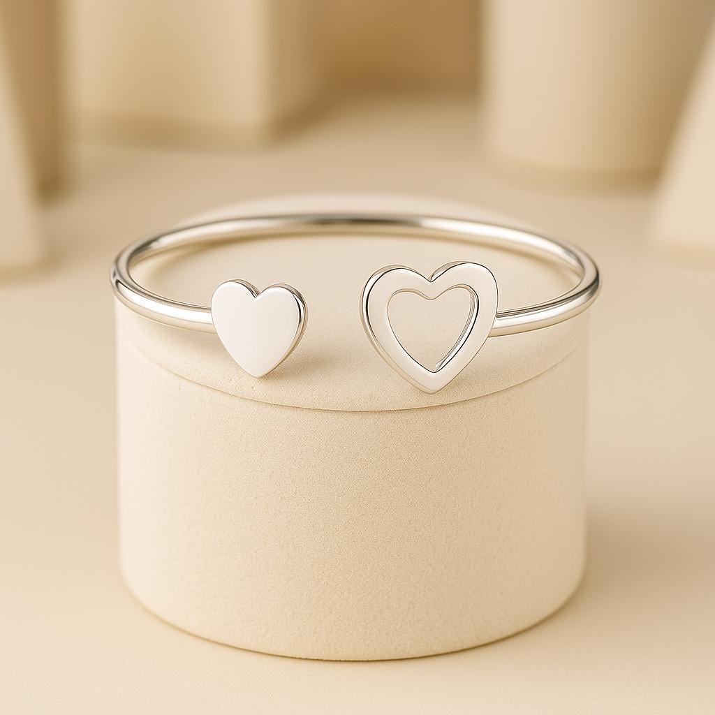Silver bangle with heart-shaped ends on a beige background