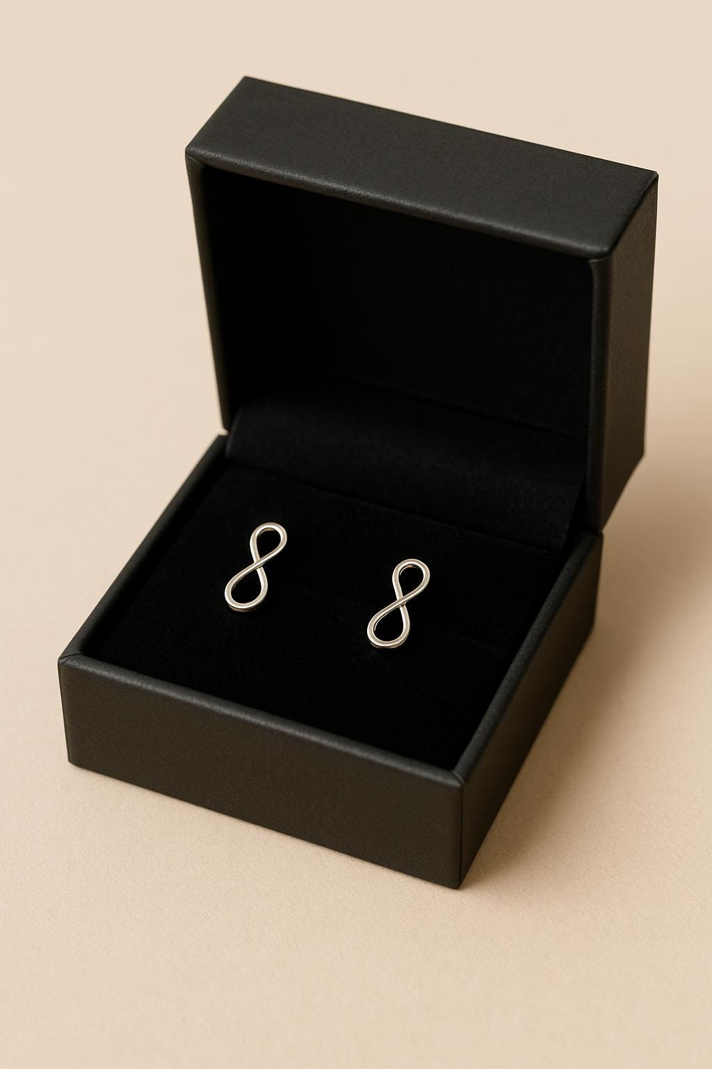 Black box with silver earrings on a beige background