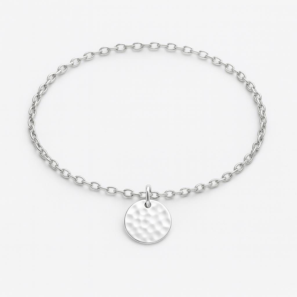Silver bracelet with a round, textured charm on a light gray background